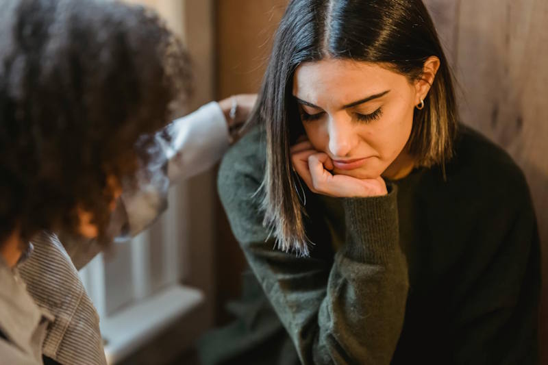 Femme triste évitant le regard de son partenaire, illustrant le danger du silence boudeur et la nécessité de briser le manque de communication dans le couple