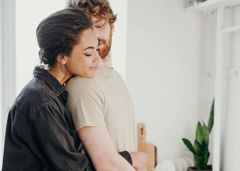 Femme enlacant tendrement son partenaire dans la cuisine, illustrant l’importance de montrer à un homme qu’il compte dans la relation