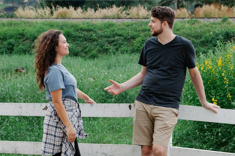 Couple échangeant tranquillement à l’extérieur près d’une clôture blanche, symbole d’une communication respectueuse après avoir appliqué le silence radio