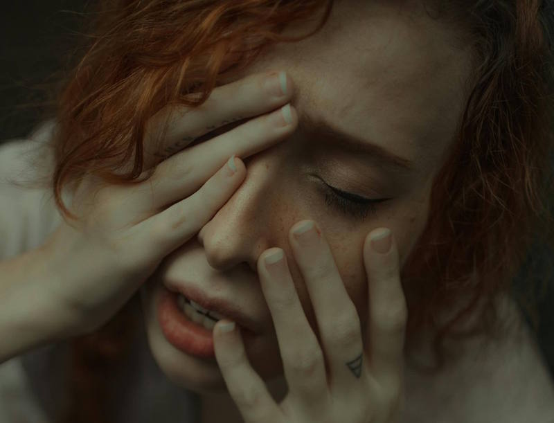 Femme aux cheveux roux affichant tristesse et détresse, illustrant l’importance de se reconstruire émotionnellement après une rupture amoureuse