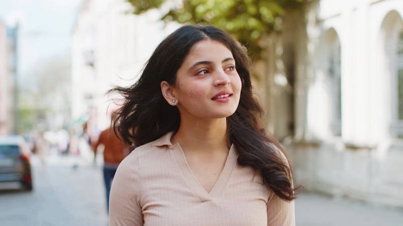 Jeune femme marchant pensive en ville, exprimant introspection et calme alors qu’elle réfléchit à sa relation pour reconquérir son ex petit ami