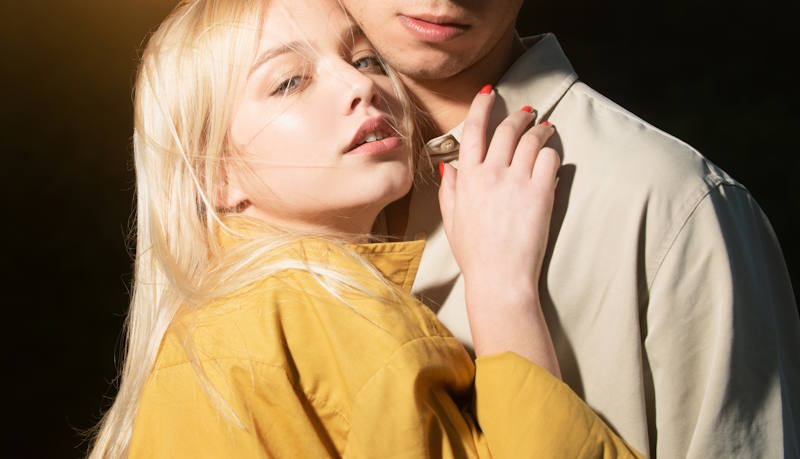 Femme blonde songeuse et homme sérieux dans les bras l’un de l’autre, symbole de comportements codépendants chez les couples