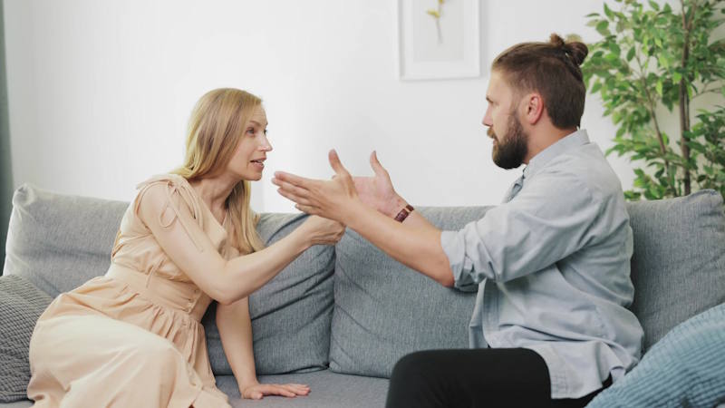 Homme manipulant sa partenaire lors d’une conversation tendue sur le canapé